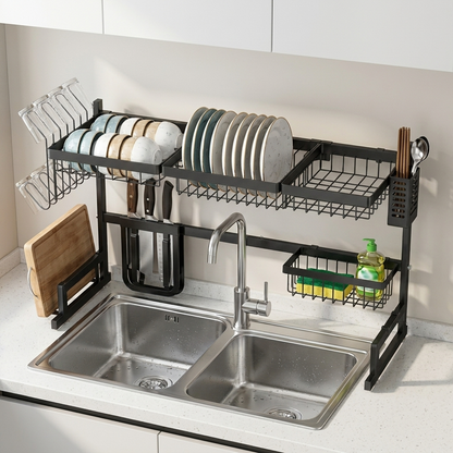 Égouttoir à vaisselle extensible noir mat installé au-dessus d'un évier double bac avec verres, bols, assiettes, couteaux et planche à découper